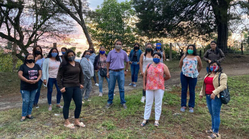 A group of specialty coffee growers from the Cauca region of Colombia standing outdoors with Dr. Alveiro Salamanca Jiménez, all wearing masks and gathered during a field visit.