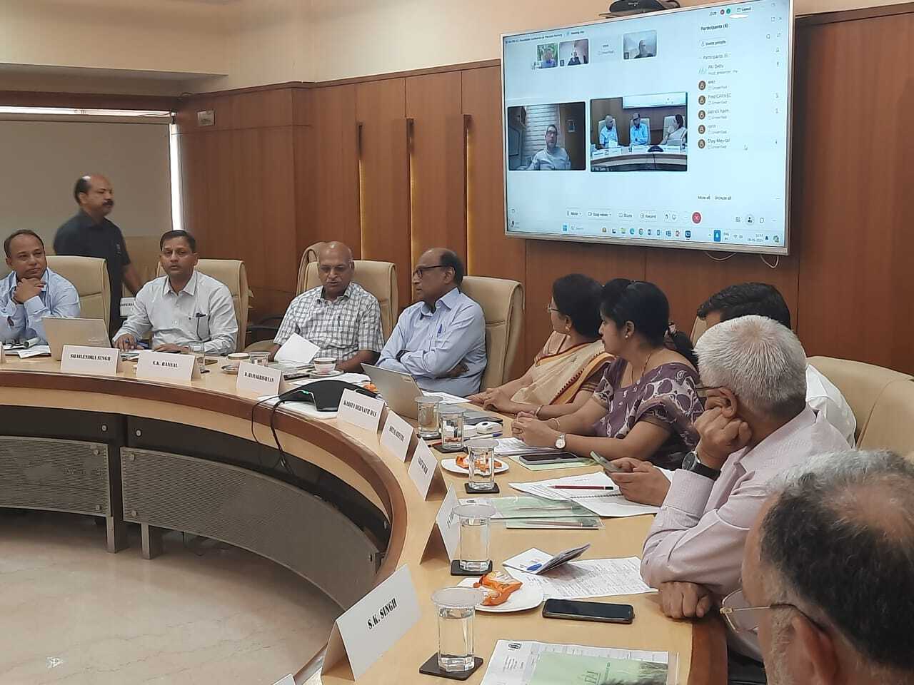 Participants at a roundtable on precision farming organized by the Fertiliser Association of India, discussing policy and technology while a video conference screen shows remote attendees in a hybrid meeting setting.