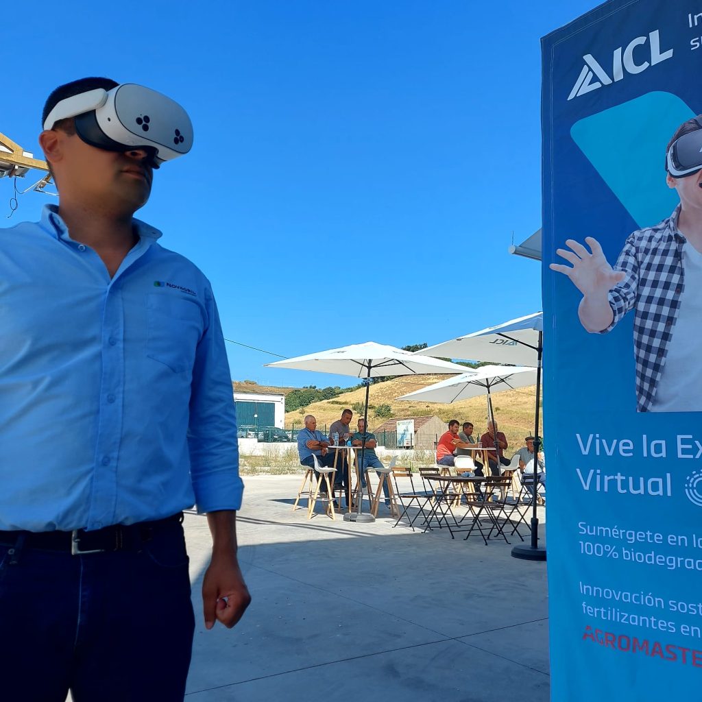 Farmer wearing a virtual reality headset at an outdoor ICL Growing Solutions Ferti-Tour event, demonstrating immersive technology used to explain fertiliser and biostimulant performance, with other farmers seated in the background.